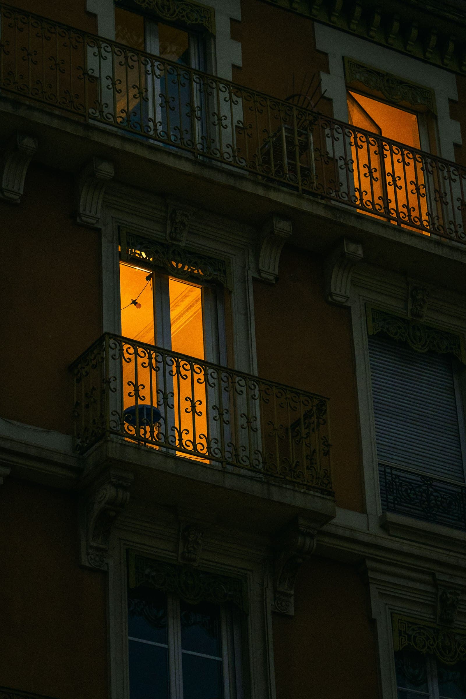 Fachada de un edificio con un balcón iluminado al anochecer